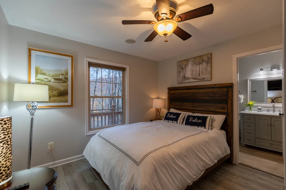 A serene bedroom with a comfortable bed, a large window letting in natural light, a bedside lamp, and subtle artwork. The room feels bright and relaxing, providing a perfect spot to unwind after a day of adventure.