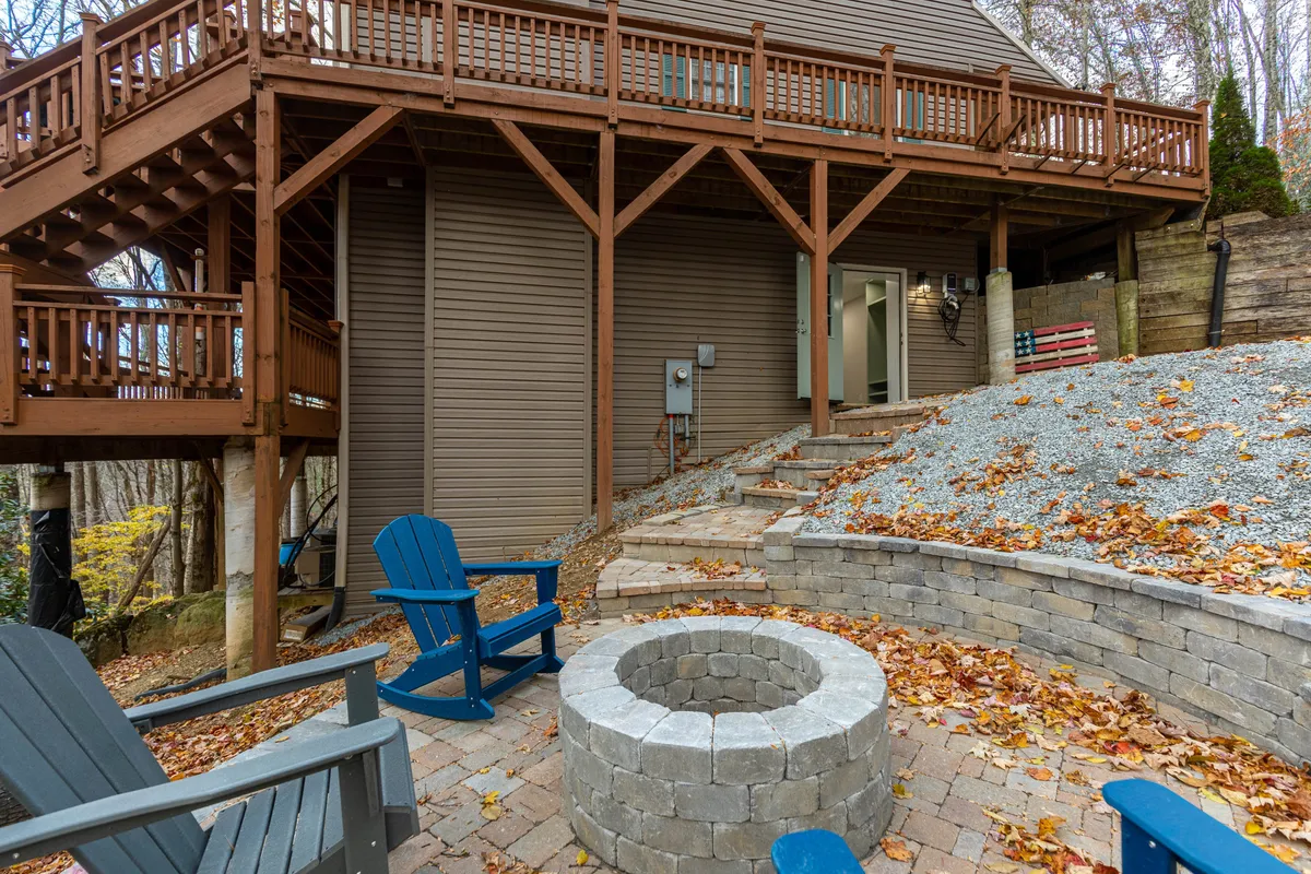 This image features a cozy outdoor seating area with a fire pit and surrounding chairs, all set on a deck with stone steps and enveloped by nature. The environment is inviting and communal, ideal for group gatherings after outdoor adventures.