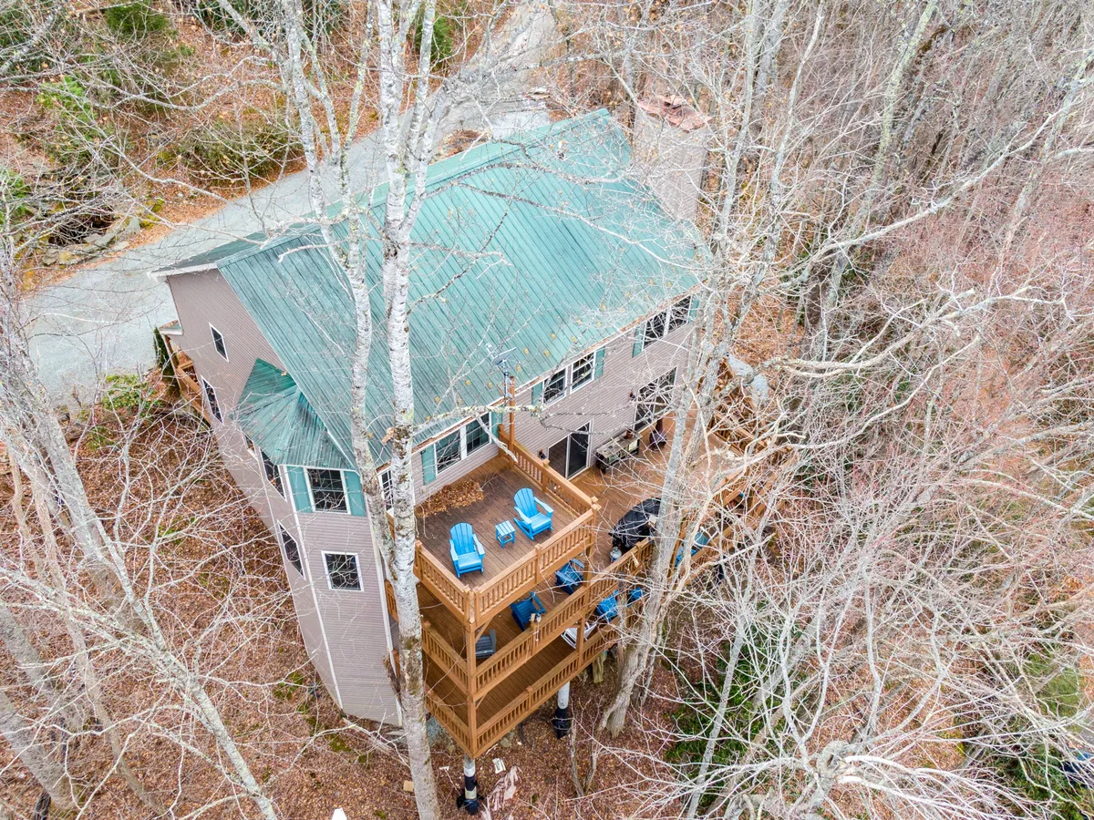 A tranquil shot showing the house’s spacious deck with comfortable chairs, set against a backdrop of dense trees. The setup conveys an inviting space for sipping coffee, enjoying the fresh air, or simply taking in the surrounding views.